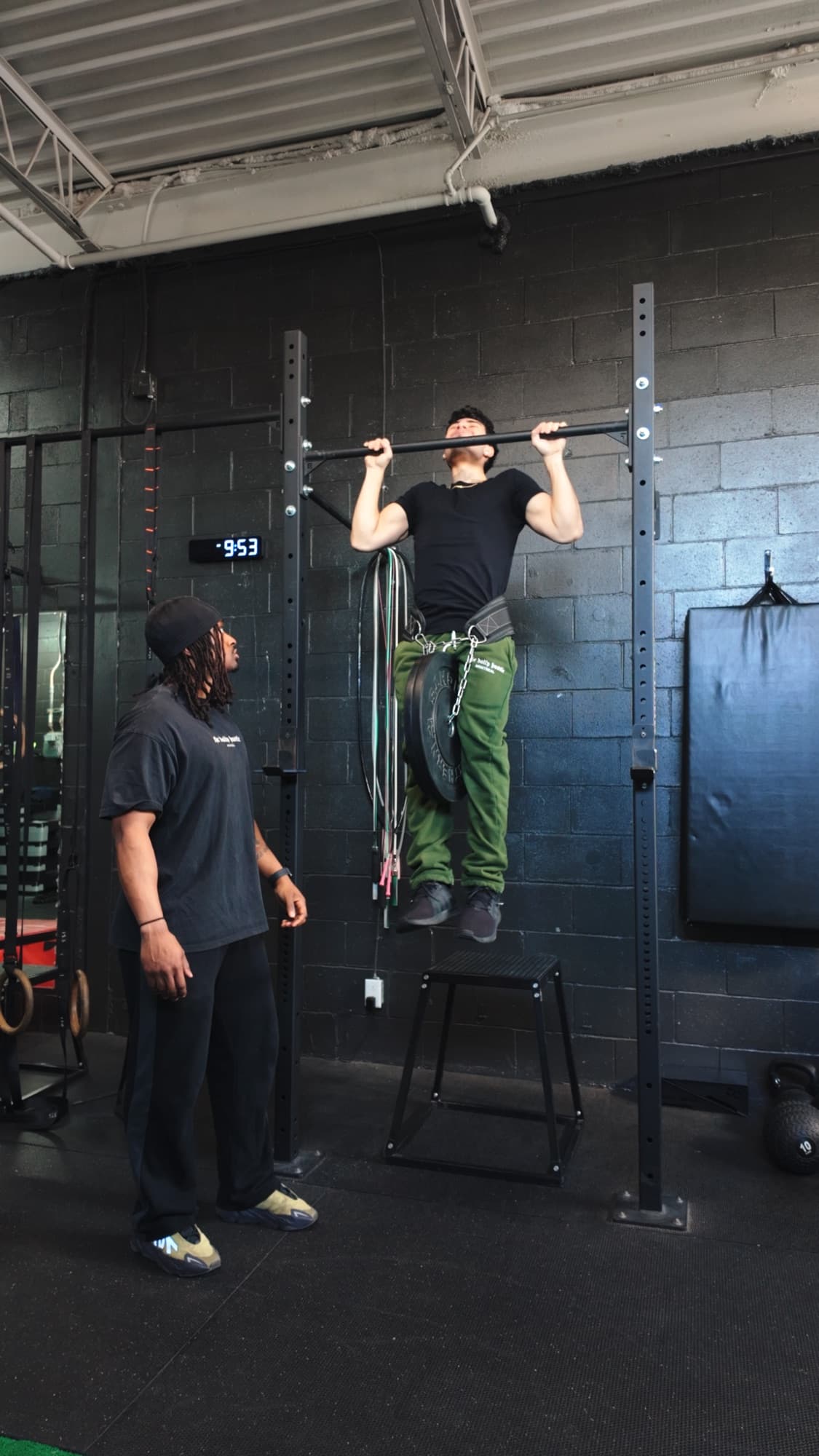 Zu coaching a client through a weighted pull-up